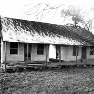 Clapboard dogtrot-style house with brick chimney and trees