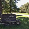 "C.A.S.S. Job Corps" sign on rock base flanked by shields on grass