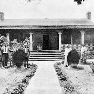 Three black men and two black women pose in landscaped yard outside home with wide porch