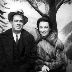 white man and woman in formal winter clothing posing by painted  nature backdrop