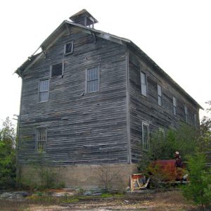 old wooden building with pane windows and crumbling roof