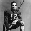 signed photo of white man in football uniform number 12 kneeling with right hand resting on helmet