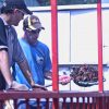 White man in cap and sunglasses watching white man in cap and sunglasses with crawfish in a shovel