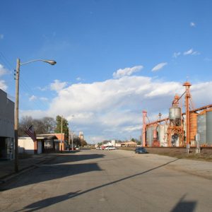 street with buildings on one side and silos on the other