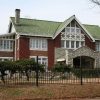 Two story brick house with tile roof stone porch large windows iron fence