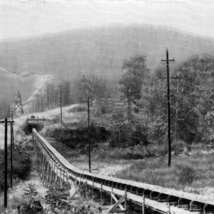 conveyer belt on wooded hillside leading to tunnel