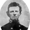 Portrait of young white man with beard in military uniform