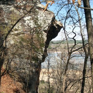 Rock face in wooded area with lake in the distance