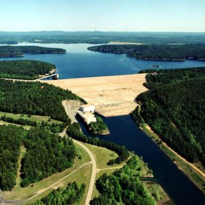 aerial view of lake with dam and tree covered shores