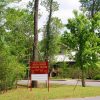 sign amid trees "Delta Rivers Nature Center" by road running in front of two-story structure