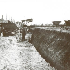 Miners digging trench with rail carts