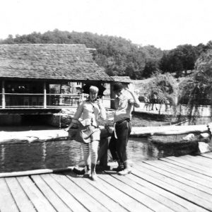 White man and woman performers on wooden bridge in park