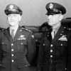 Two white men in military uniform posing with a car behind them