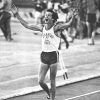 White male track athlete "Arkansas state" jersey celebrates smiling hands raised people in background field