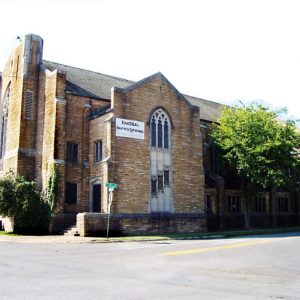 Multistory brick and stone church with arched stained glass windows and sign saying "Emoba's Haunted Cathedral"