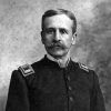 White man with mustache standing in military uniform