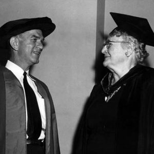 White man and woman smile chat in academic caps and gowns