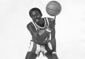 African-American man in basketball jersey uniform spinning a basketball on one finger