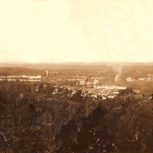 Factory town with warehouses neighborhood smoke plume and hillside buildings viewed from hill