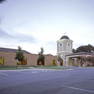 Single-story church with two-story tower and parking lot