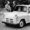 two white men stand next to small white truck