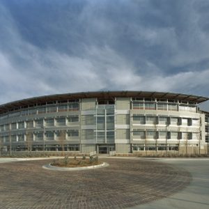 Four story curved architectural building with roundabout brick driveway and landscaping cloudy sky