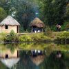 White visitors with grass pavilion and round hut on lake