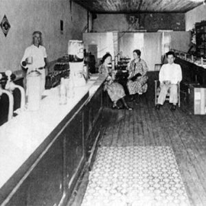 Two white men and three white women in cafe with shelves and bar