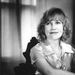 White woman with curly hair sitting in a chair