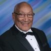 Older African-American man with glasses smiling in tuxedo