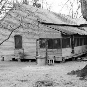 Wood frame house with metal roof screened porch crawl space well coop and large tree