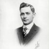 Vignette portrait photograph of a young white man in a shirt tie vest and jacket with his hair in a pompadour