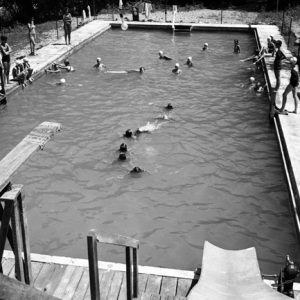 girls swimming in in-ground swimming pool with a diving board