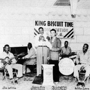 African American men play in a band in front of banner reading "King Biscuit Time"