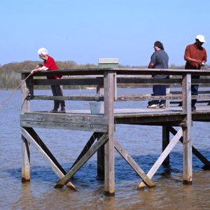 three people fishing off a dock