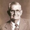 older white man in glasses  wearing checkered suit and tie