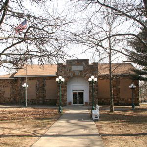 stone building with glass doors flying American flag outside