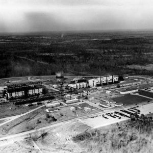 Aerial view of an industrial complex with various buildings and machinery with roads plains and horizon in background