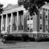 Multistory brick building with classical columns and war monument statue with figure of man on top