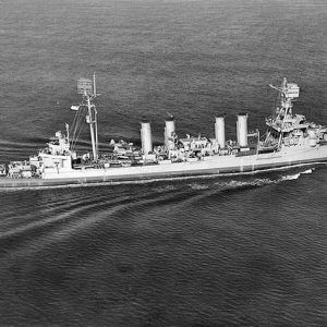 Aerial view of naval ship with four smokestacks underway at sea