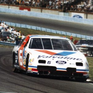 "Valvoline" stock car on race track with crowd in the background