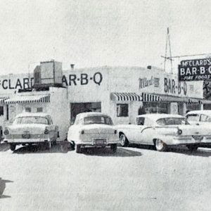 Single-story white restaurant building with sign and cars in parking lot