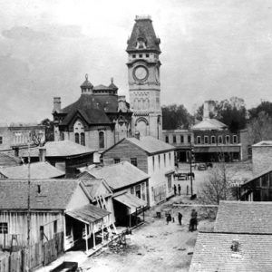 Street scene featuring  wood framed houses and downtown brick architecture and large clock towner in background