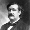 Portrait photo of a white man with a dark mustache brushed hair solemn expression in suit and bow tie