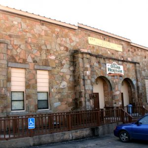 stone "Ozark Heritage" building with blue car in front