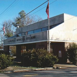 Brick and concrete building on street with flag pole