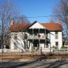 tw- story wooden house with Christmas wreath and white fence