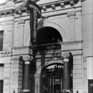 Multistory stone building with hanging  "Historical Museum" sign Greek facade gate arches and parking meter