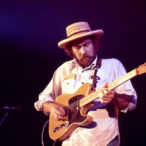 White man with long hair and beard in a hat playing a Fender Telecaster style electric guitar on stage