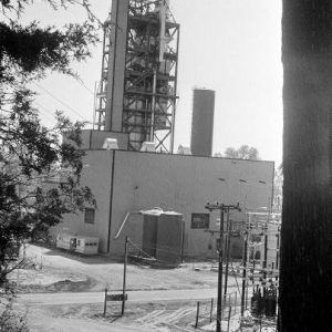 Industrial building with tall steel stairwell structure and power substation with foreground trees